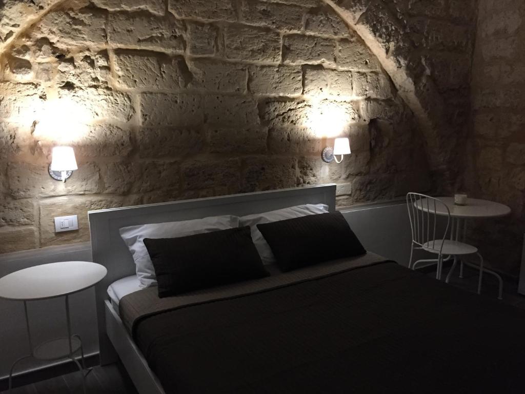a bedroom with a bed and two tables and a stone wall at B&B 62 Marinai in Bari