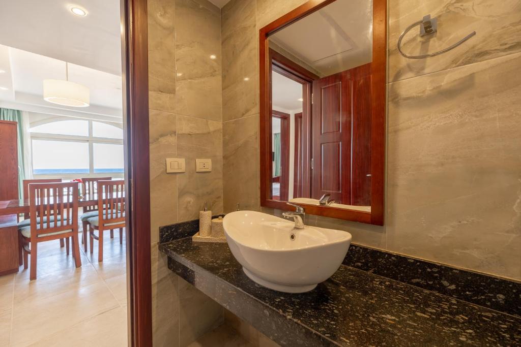 a bathroom with a sink and a mirror at Oyster Bay Beach Suites in Abu Dabbab