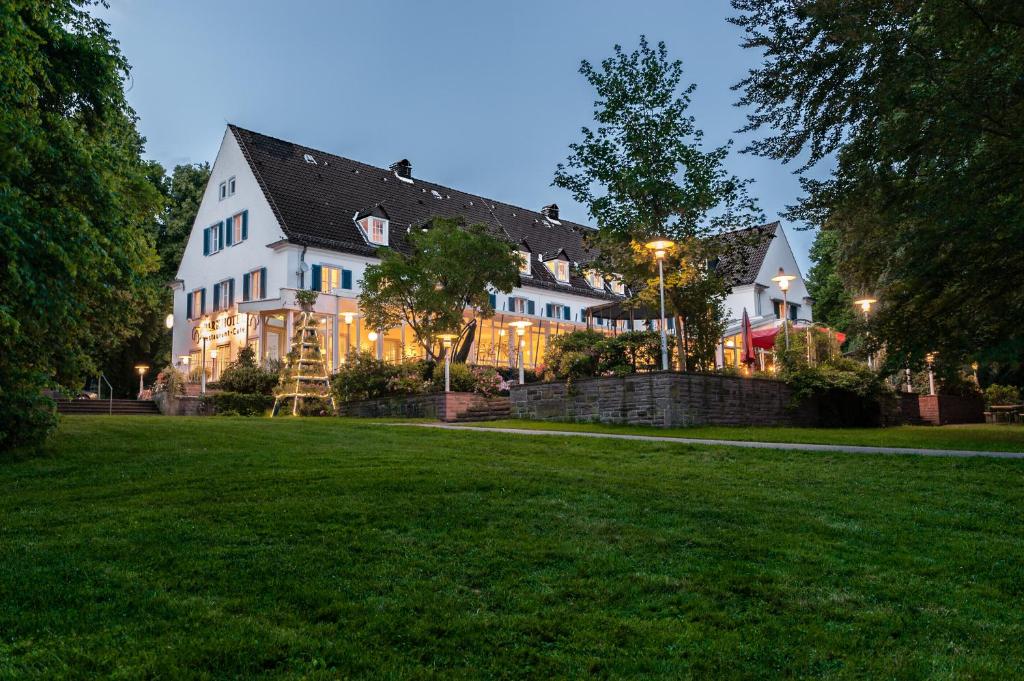 une grande maison blanche avec une pelouse devant elle dans l'établissement Parkhotel Wolfsburg, à Wolfsburg