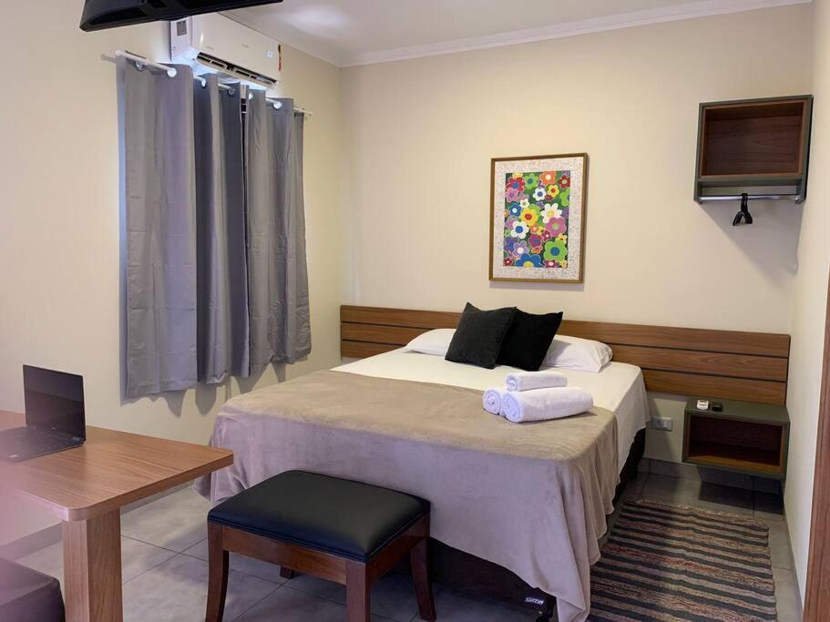 a bedroom with a bed with a chair and a table at Studio Standard l AO LADO SHOPPING in Três Lagoas