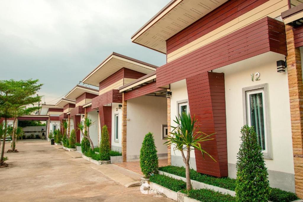 une rangée de maisons avec des arbres devant elles dans l'établissement Buengngarm Resort, à Ban Sok Pho