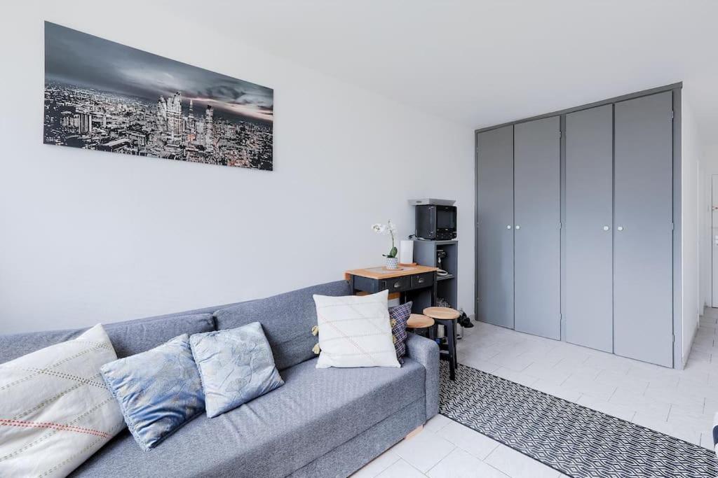 un salon avec un canapé gris et une table dans l'établissement Studio Cosy à La Défense Confort et Accessibilité, à Courbevoie