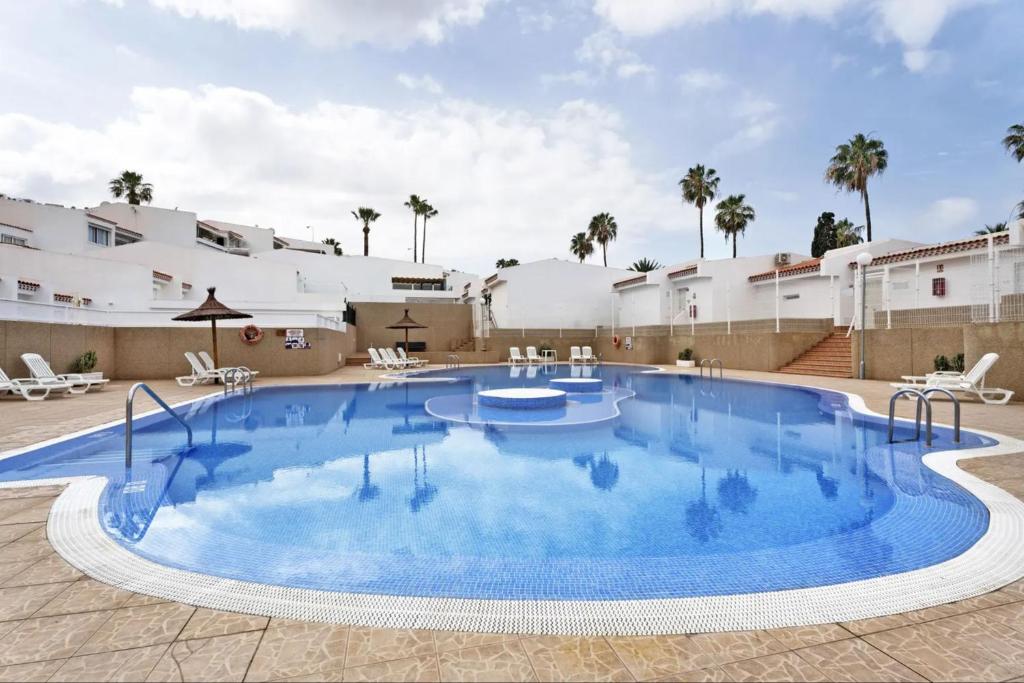 a large pool with blue water in a courtyard at Child-friendly, 3-bedroom apartment with garden near the Aqualand in Adeje
