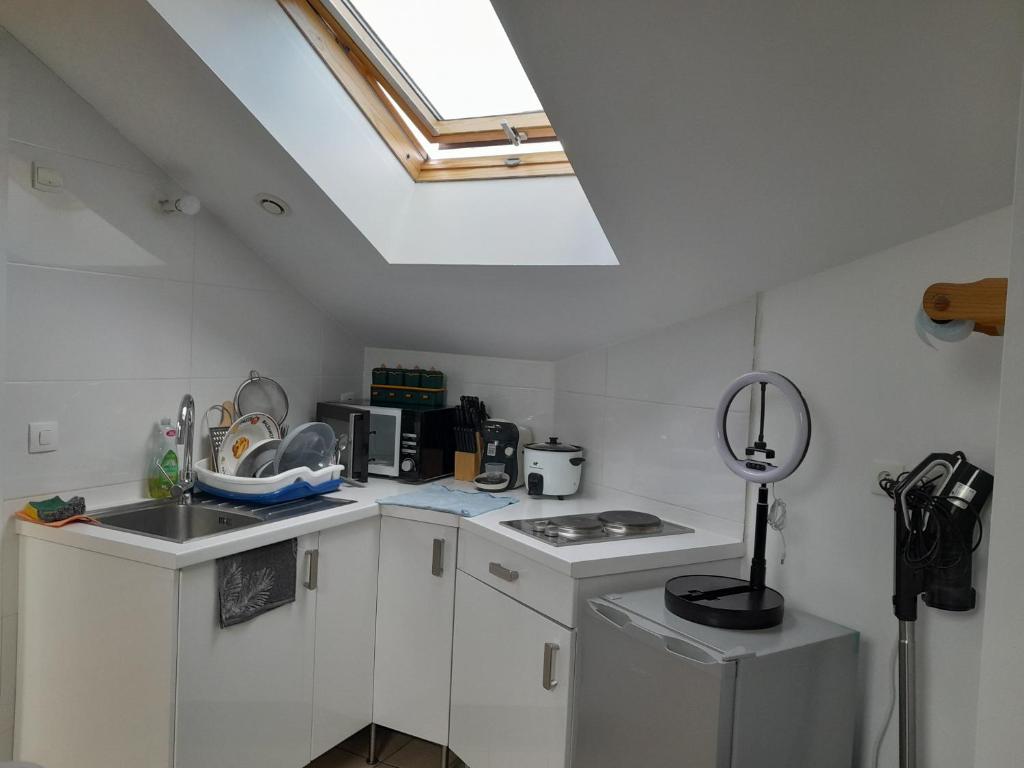 a kitchen with white cabinets and a skylight at Appartement meublé à 30 minutes de Paris in Mantes-la-Jolie