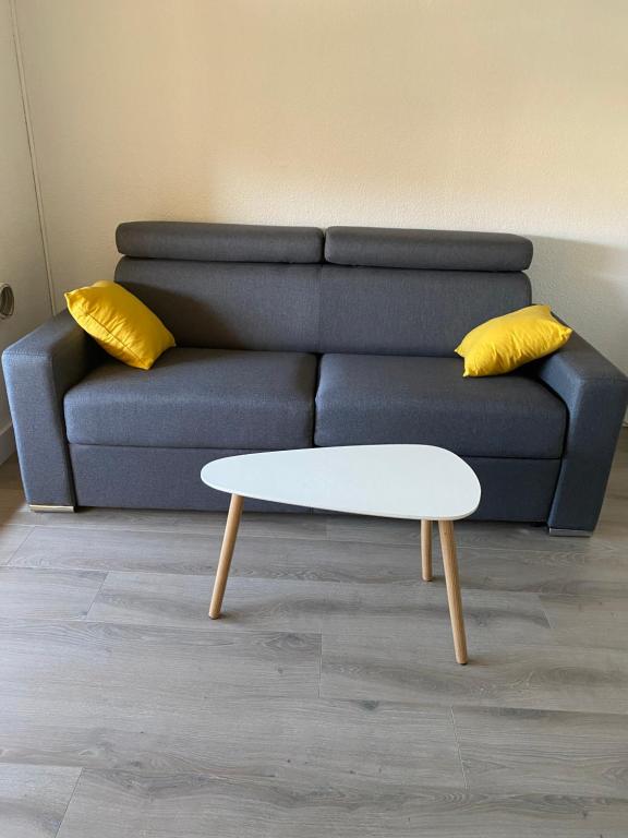 un canapé bleu avec des coussins jaunes et une table basse blanche dans l'établissement Beverley hills, au Cap d'Agde