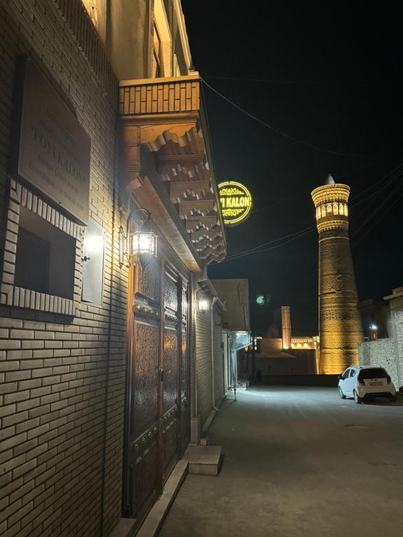 un bâtiment en briques avec une tour d'éclairage en arrière-plan dans l'établissement Hotel POYI KALON terrace حلال, à Boukhara