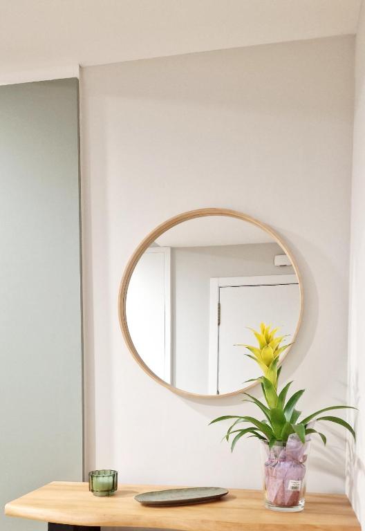 a mirror on a wall above a table with a plant at Laralva Home in Pontevedra