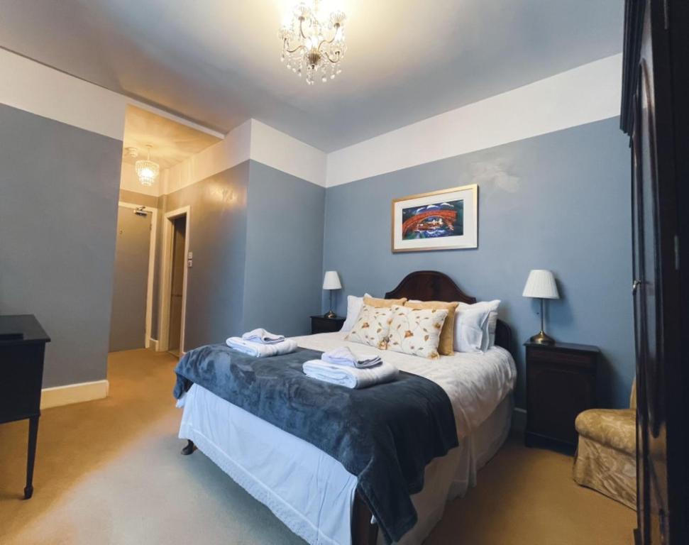 Un dormitorio con una cama con paredes azules y una lámpara de araña. en Wavecrest, en Barmouth