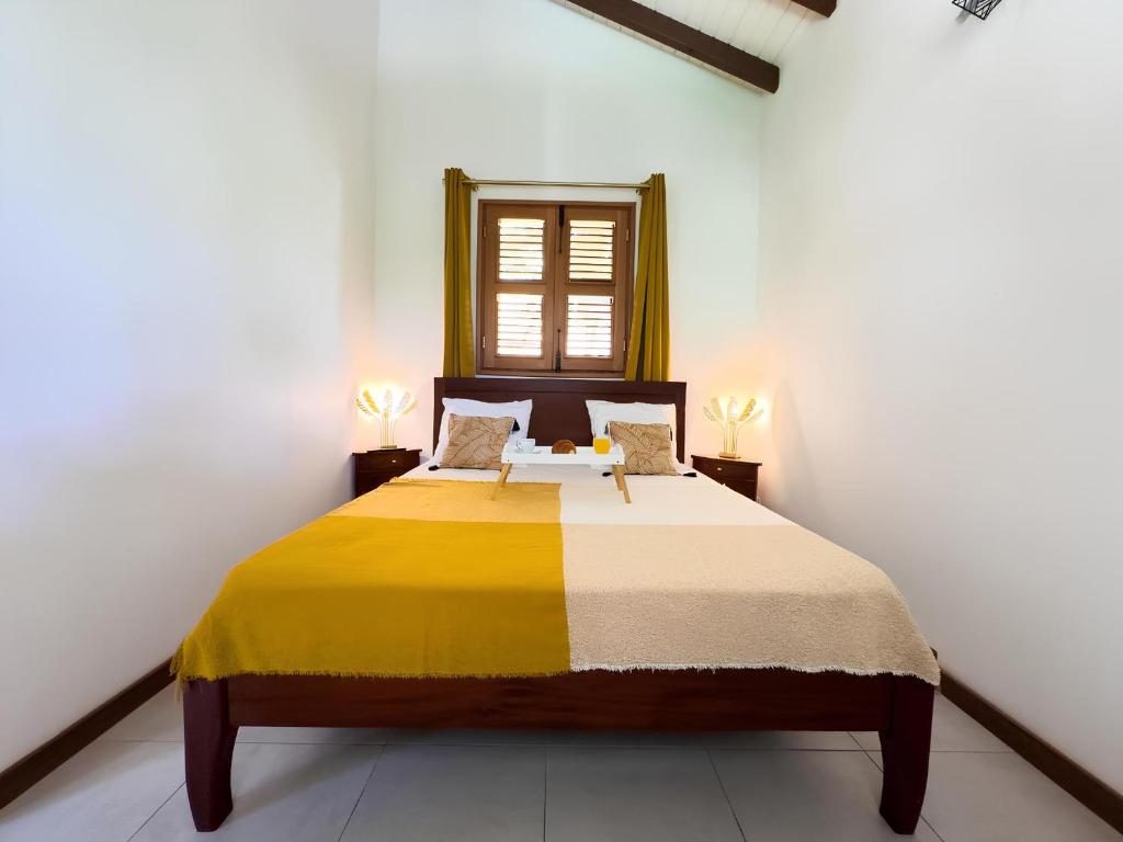 um quarto com uma cama grande e um cobertor amarelo em Bungalow le Balisier em Pointe-Noire