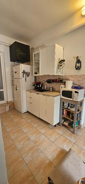 uma cozinha com um frigorífico branco e piso em azulejo em Club Biliard em Bicaz
