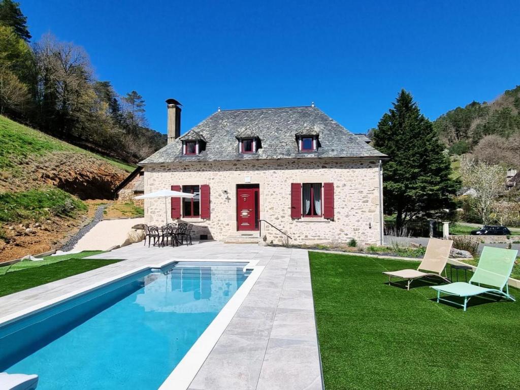 une maison en pierre avec une piscine en face de celle-ci dans l'établissement Gîte de France L'air du paradis 3 épis - Gîte de France 6 personnes 344, à Argentat