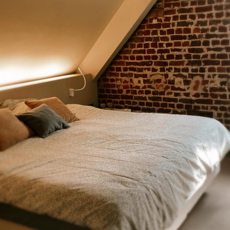 a bed in a room with a brick wall at B&B Park Rodenbach in Roeselare