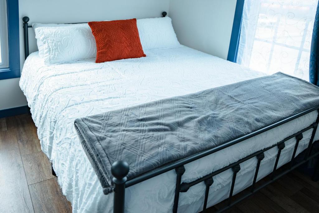 1 cama con edredón blanco y almohada naranja en Van Wormer Room 201, Hyland Hotel en Palmer