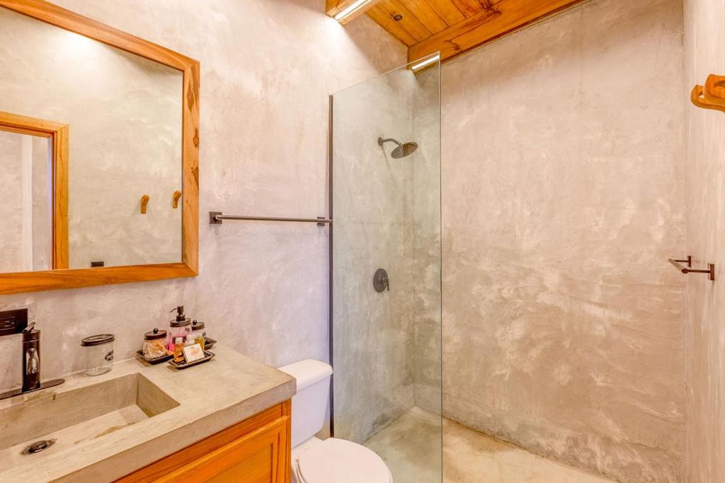 a bathroom with a shower and a toilet and a sink at Seabird Dwellings Villa with Private Splash Pool and Dock in Placencia Village