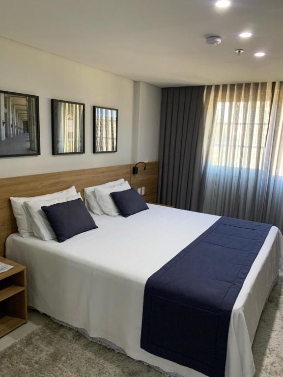 a bedroom with a large white bed with blue pillows at Apartamento Hotel Itaipava Petropolis in Petrópolis