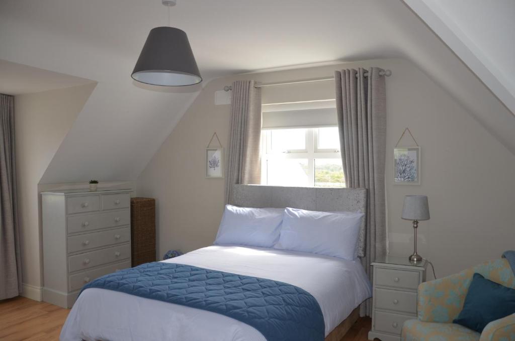 a bedroom with a bed and a chair and a window at Enniscrone Luxury Double Room in Enniscrone