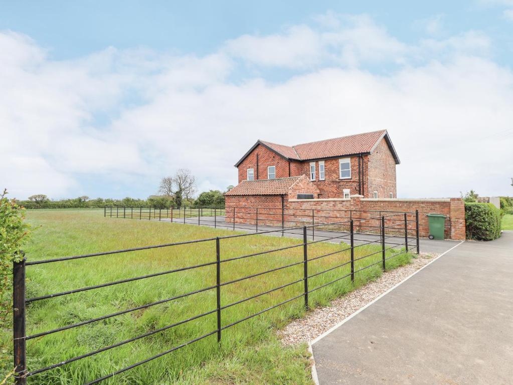 a brick house with a fence in front of a field at Foremans Cottage in Hull