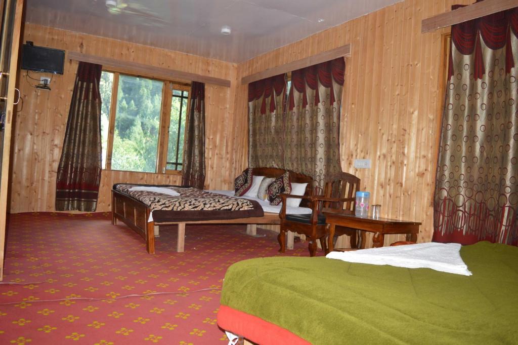 a bedroom with a bed and a bench and a window at Hotel Gulfam Palace in Pahalgām