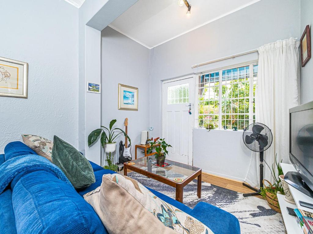 sala de estar con sofá azul y ventana en Cosy Victorian Style Full Apartment, en Ciudad del Cabo
