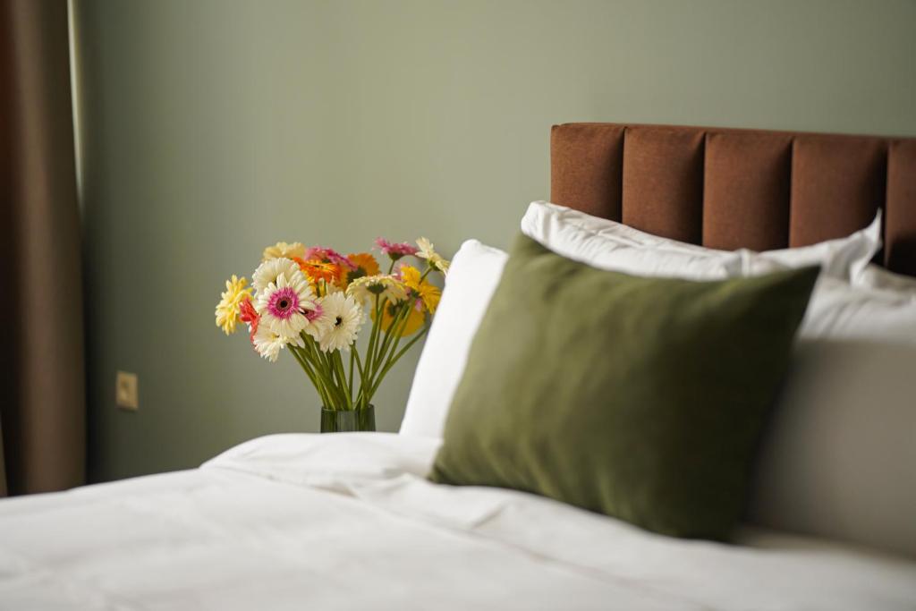a vase of flowers sitting on top of a bed at Felinger Collection Hotel & SPA in Yerevan