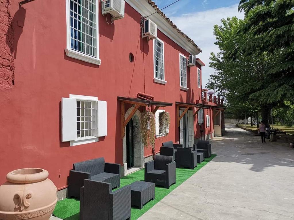 un bâtiment rouge avec des chaises noires devant lui dans l'établissement Antico Casale, à Monteforte Irpino