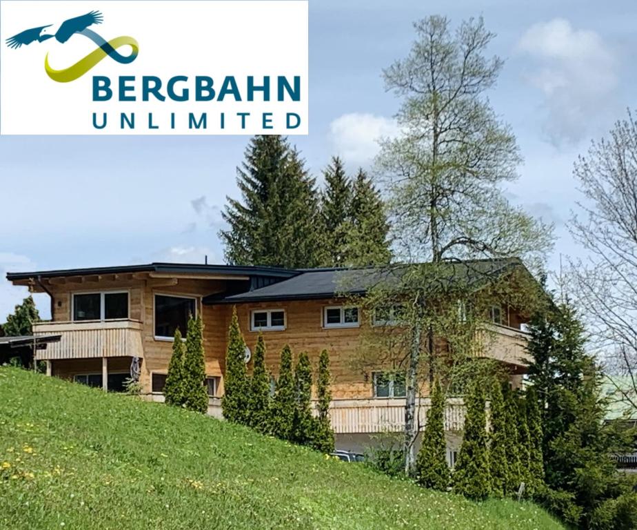 una casa di tronchi su una collina con il logo bergiselin illimitato di Ferienwohnung Riezler a Hirschegg