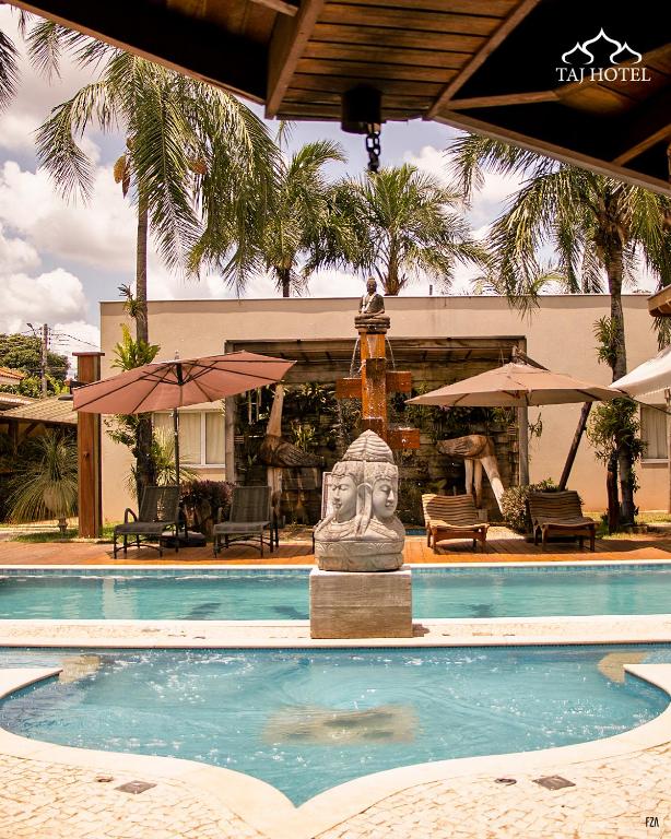 a swimming pool with a statue in front of a building at Taj Hotel in Três Lagoas
