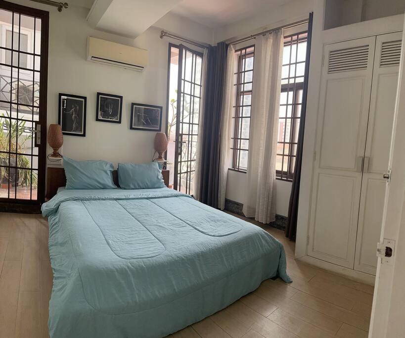 a bedroom with a bed with blue sheets and windows at Cozy 1BR in Downtown Phnom Penh BKK2 in Phnom Penh
