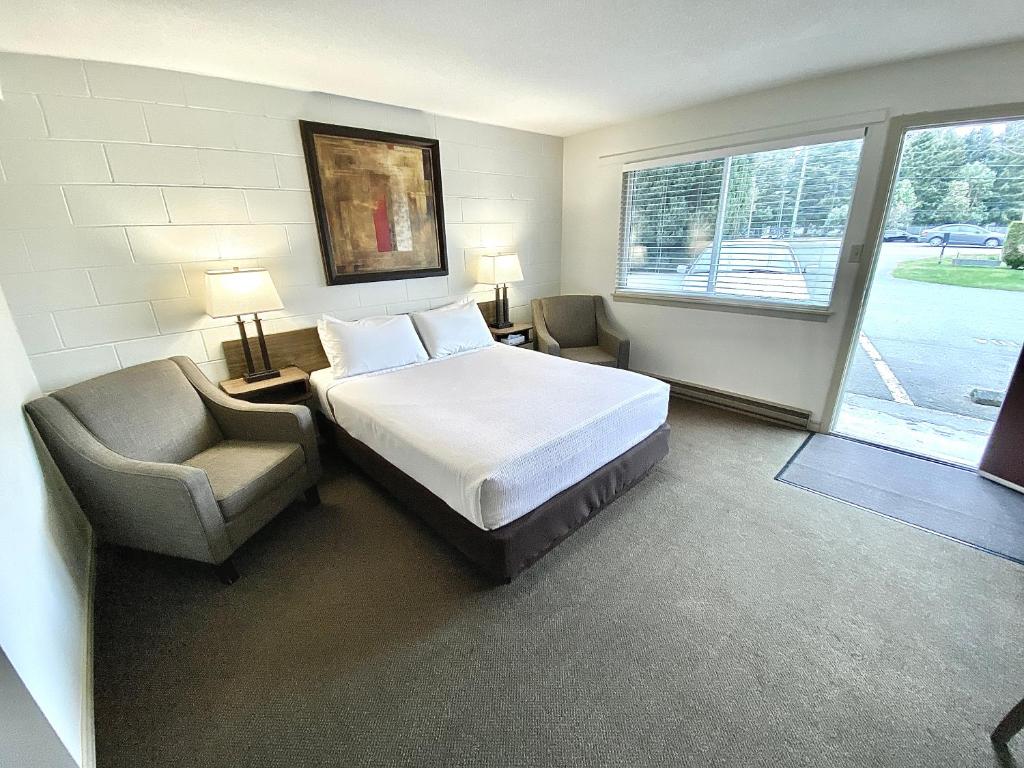 een slaapkamer met een bed, een stoel en een raam bij Arbutus Grove Motel in Parksville