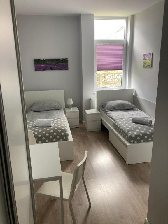 a bedroom with two beds and a chair and a window at Hostelik Przy Przystanku in Gryfino