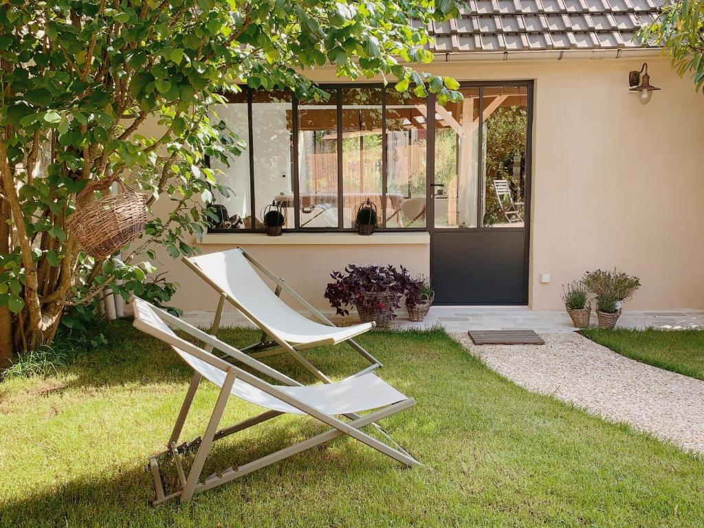 Deux chaises blanches assises dans l'herbe devant une maison dans l'établissement L'Atelier d'ici, à Thomery