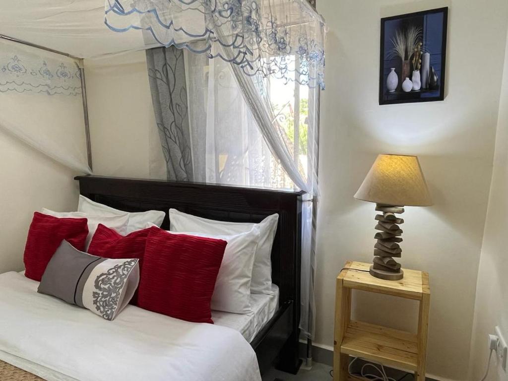 a bedroom with a bed with red and white pillows at Kindiha homes. in Seeta