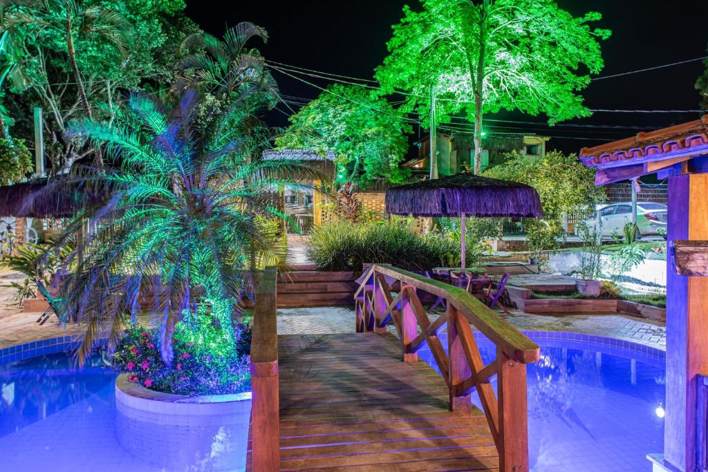 um resort com piscina, árvores e uma ponte em Pousada Das Araras em Itaúnas