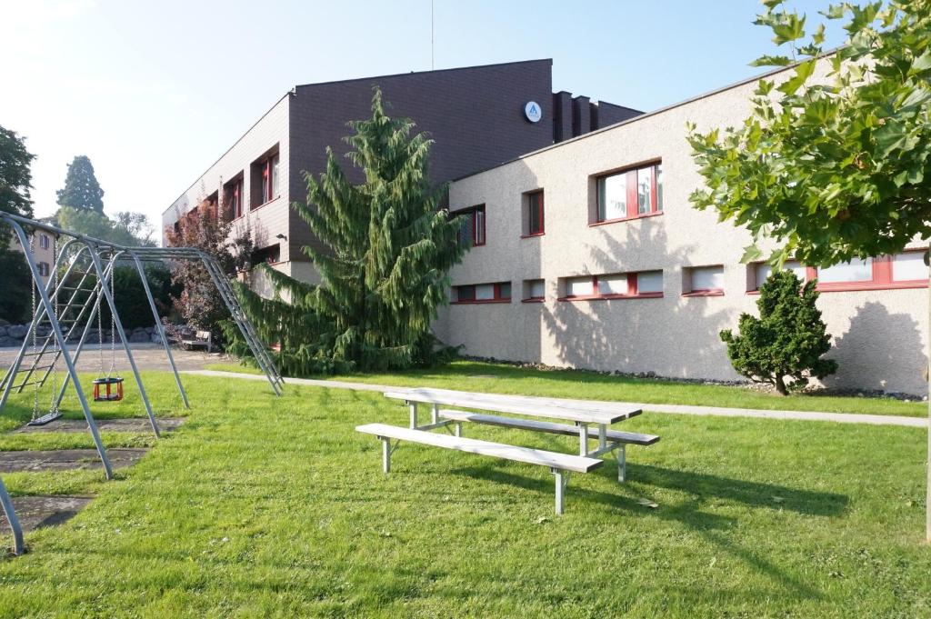 un parc avec un banc et une balançoire dans l'établissement Jugendherberge Romanshorn, à Romanshorn