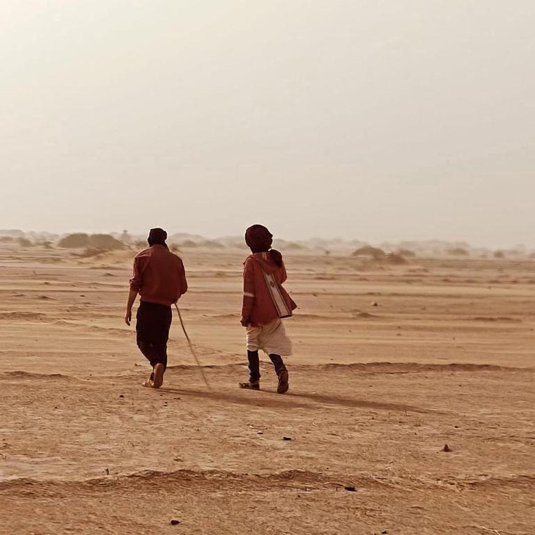two men walking in the desert with a rope at dar Brahim in Mhamid