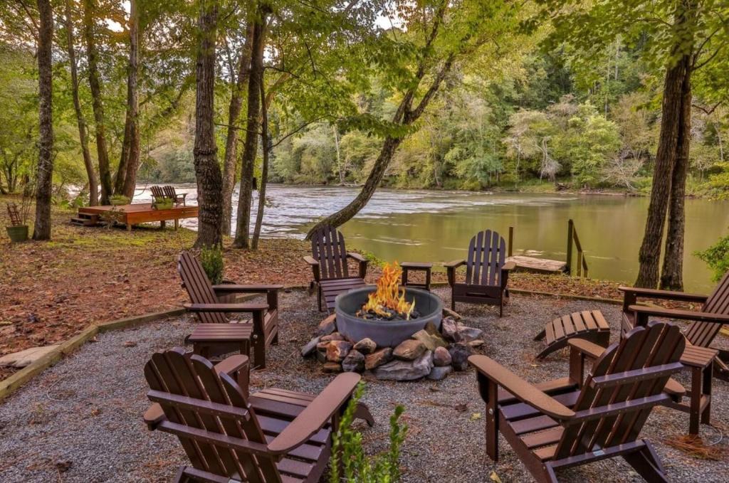 a group of chairs around a fire pit next to a river at Crescent Moon on the River in Ellijay