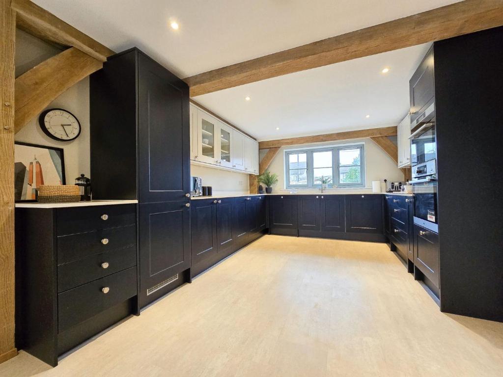 a large kitchen with black cabinets and a window at 4BR Country Home Near Cider Barn & Brewery in Axbridge