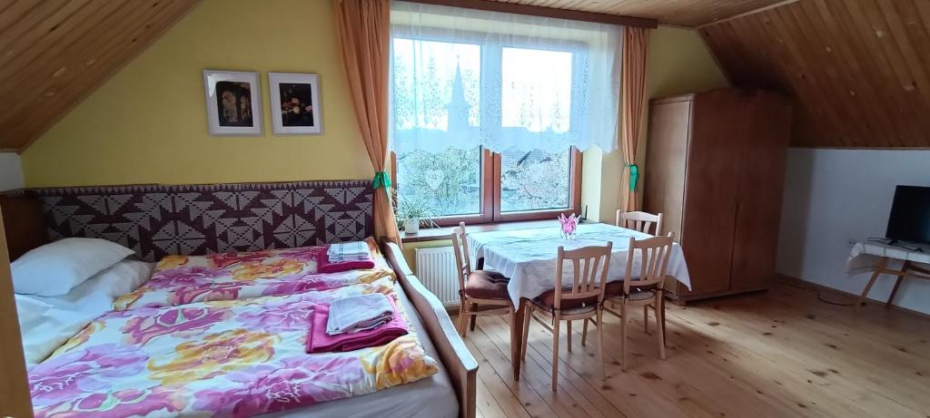 Schlafzimmer mit einem Bett, einem Tisch und einem Fenster in der Unterkunft Ubytovanie Gerlachov in Gerlachov