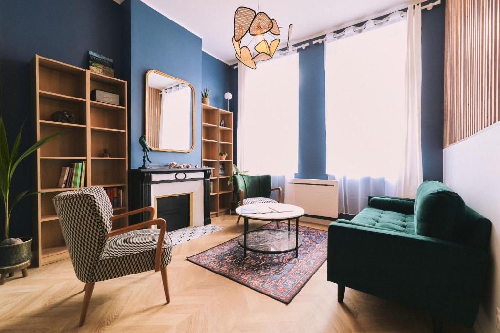uma sala de estar com paredes azuis e um sofá verde em La Maison Des Petits Sablon em Amiens