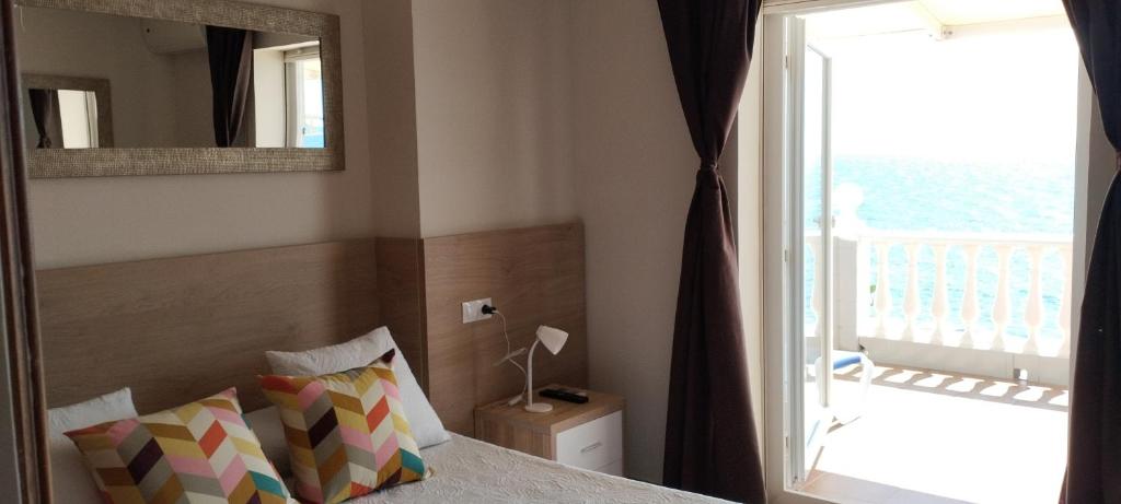 a bedroom with a bed with a mirror and a balcony at Apartamentos Don Pepe in Torremolinos