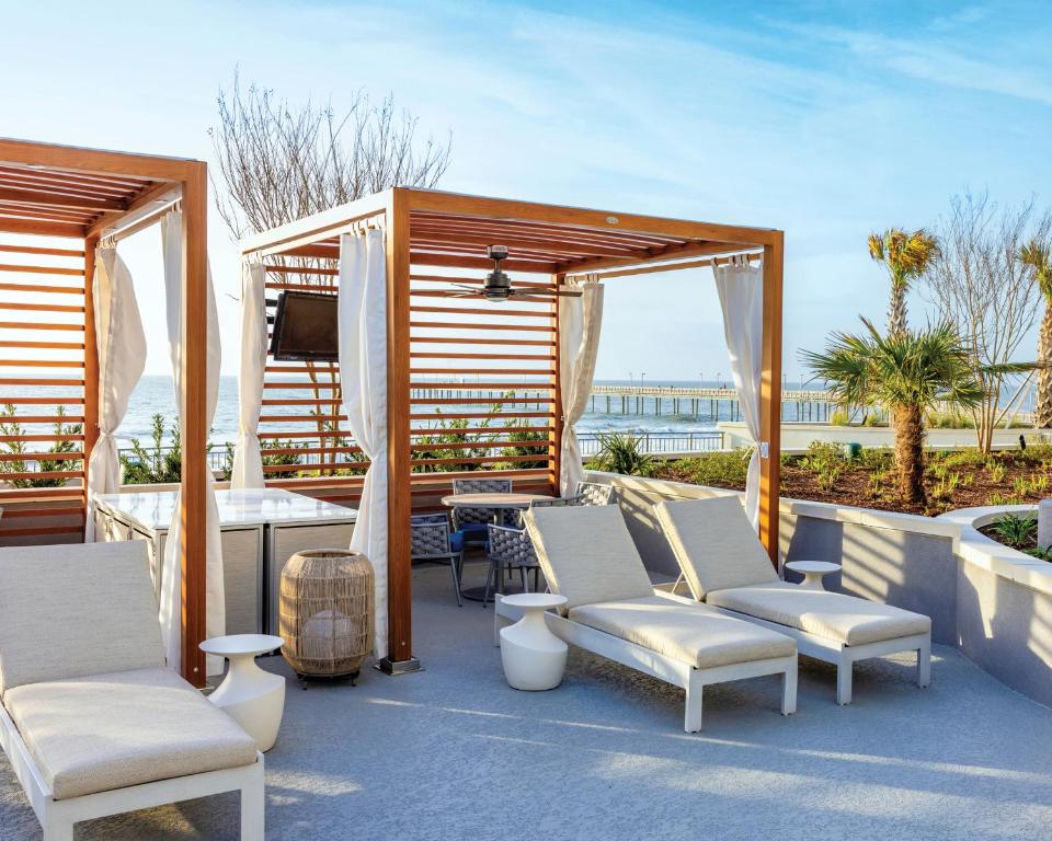 eine Terrasse mit Stühlen, einem Tisch und einem TV in der Unterkunft Holiday Inn Club Vacations Myrtle Beach Oceanfront in Myrtle Beach