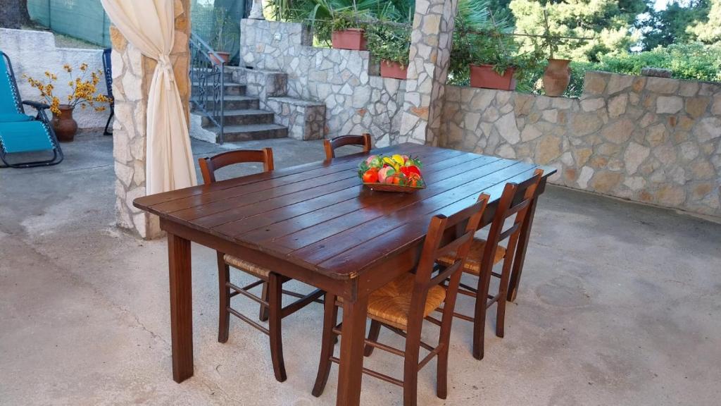 una mesa de madera con sillas y un bol de fruta. en Villa vicino Mare, en Borgo Bonsignore