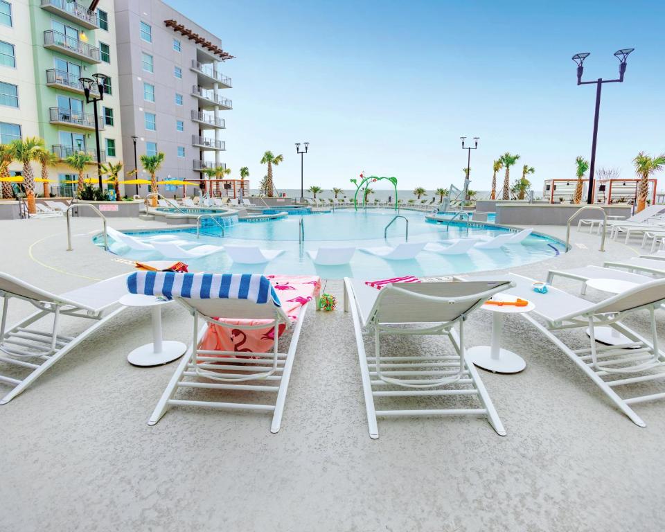 ein Swimmingpool mit Stühlen und einem Tisch und einem Tisch und Stühlen in der Unterkunft Holiday Inn Club Vacations Myrtle Beach Oceanfront in Myrtle Beach