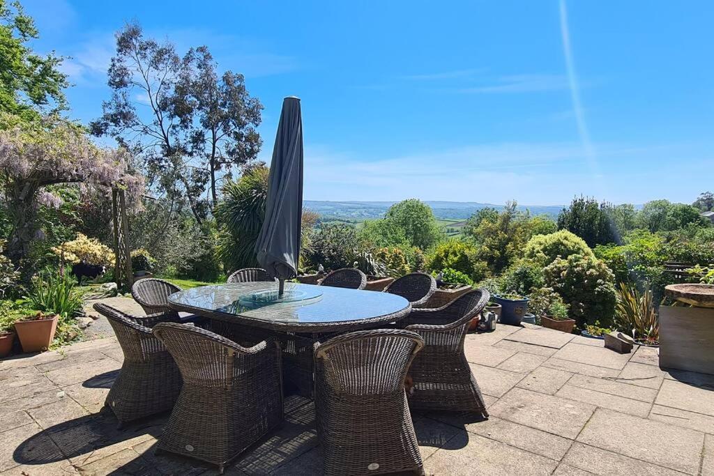 ein Tisch mit Stühlen und einem Sonnenschirm auf einer Terrasse in der Unterkunft Stunning house, fenced garden, and outdoor dining! in Hennock