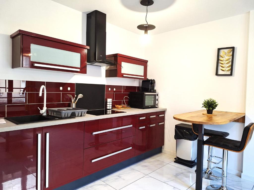a kitchen with red cabinets and a wooden table at Hypercentre Orléans Carmes in Orléans