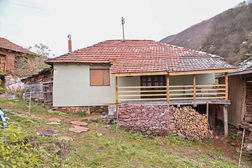 una pequeña casa con una pared de piedra delante de ella en Kuća Cvetković en Pirot