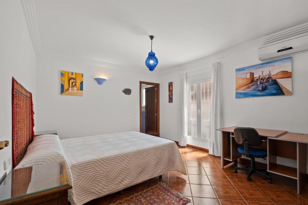 a bedroom with a bed and a desk in it at Casa El Tarajal in Málaga