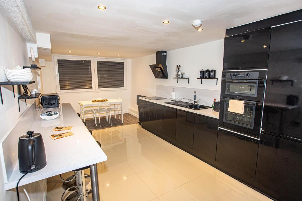 a kitchen with black cabinets and a white counter top at Beach haven retreat, Caswell Bay in Swansea