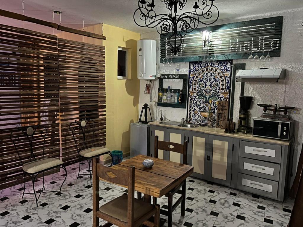 uma cozinha com mesa e cadeiras num quarto em L'artisan em Harqalah