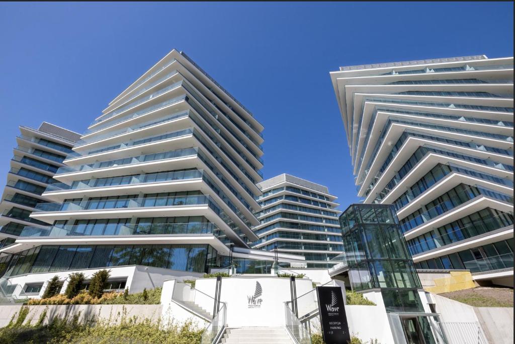 two tall buildings in front of a blue sky at Wave Sea View in Międzyzdroje